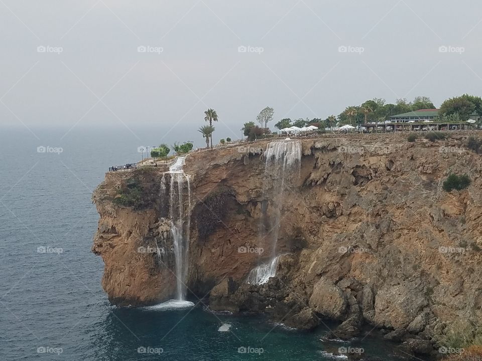 waterfalls dropping off the cliff to the sea below