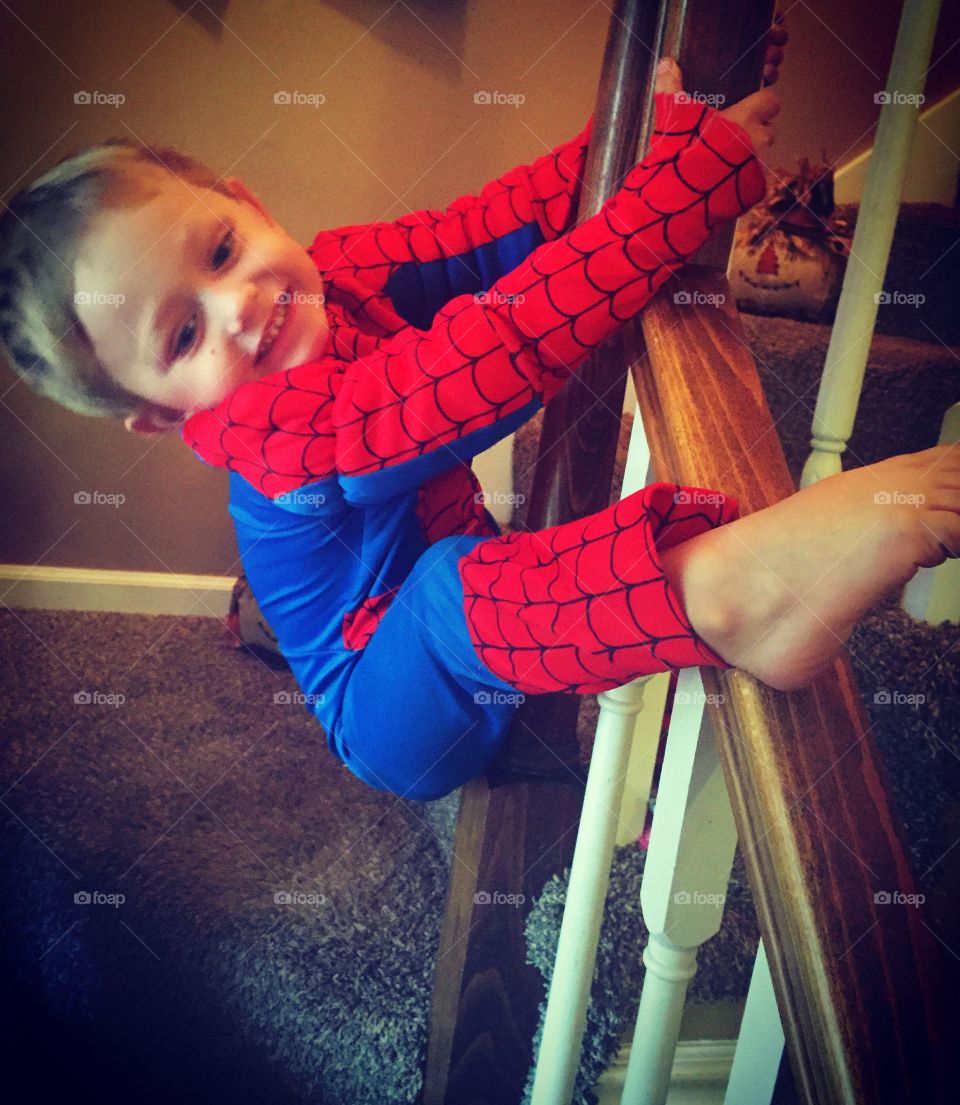 Boy with Spiderman costume hanging wooden railing