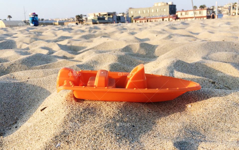 Orange toy boat on sand