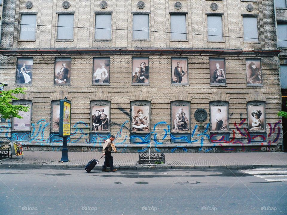 a man with a suitcase walks down the street of the city of Kiev