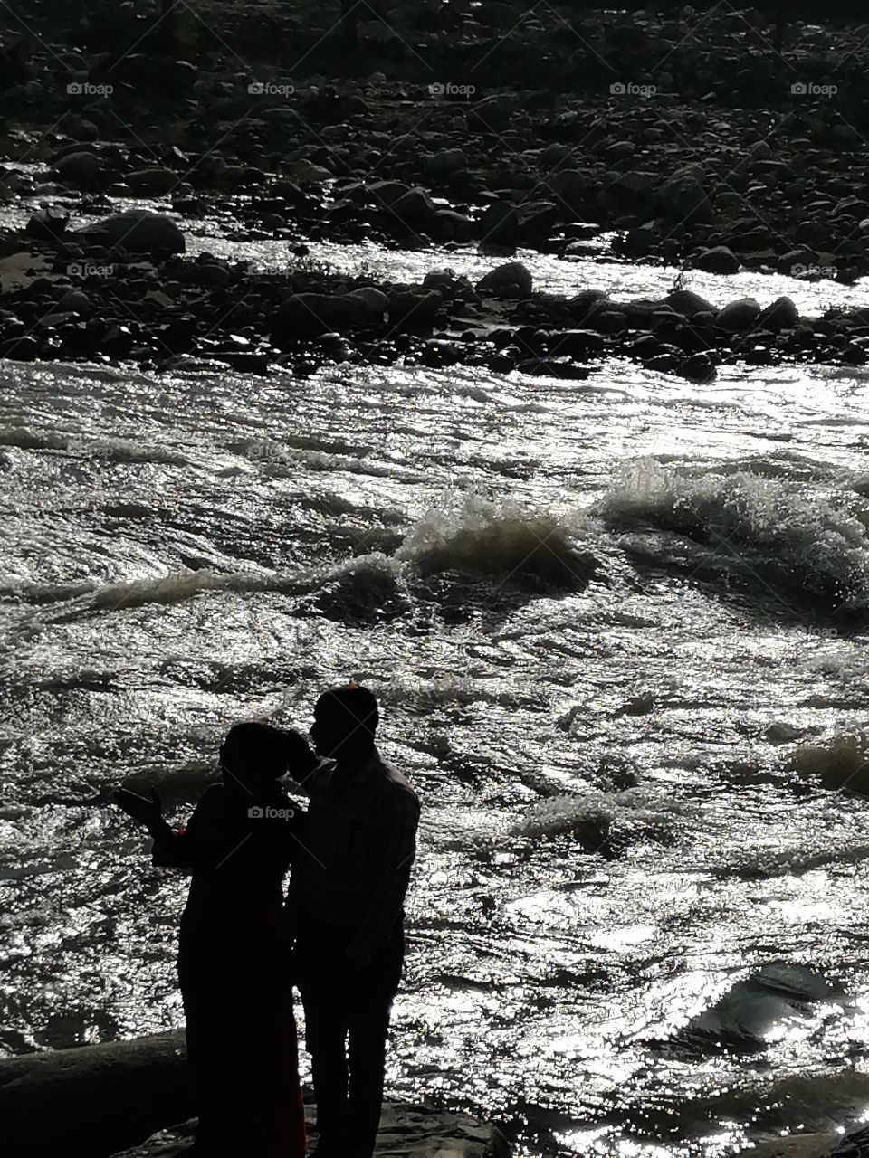 Couple standing on the bank of river and enjoying stream of river.