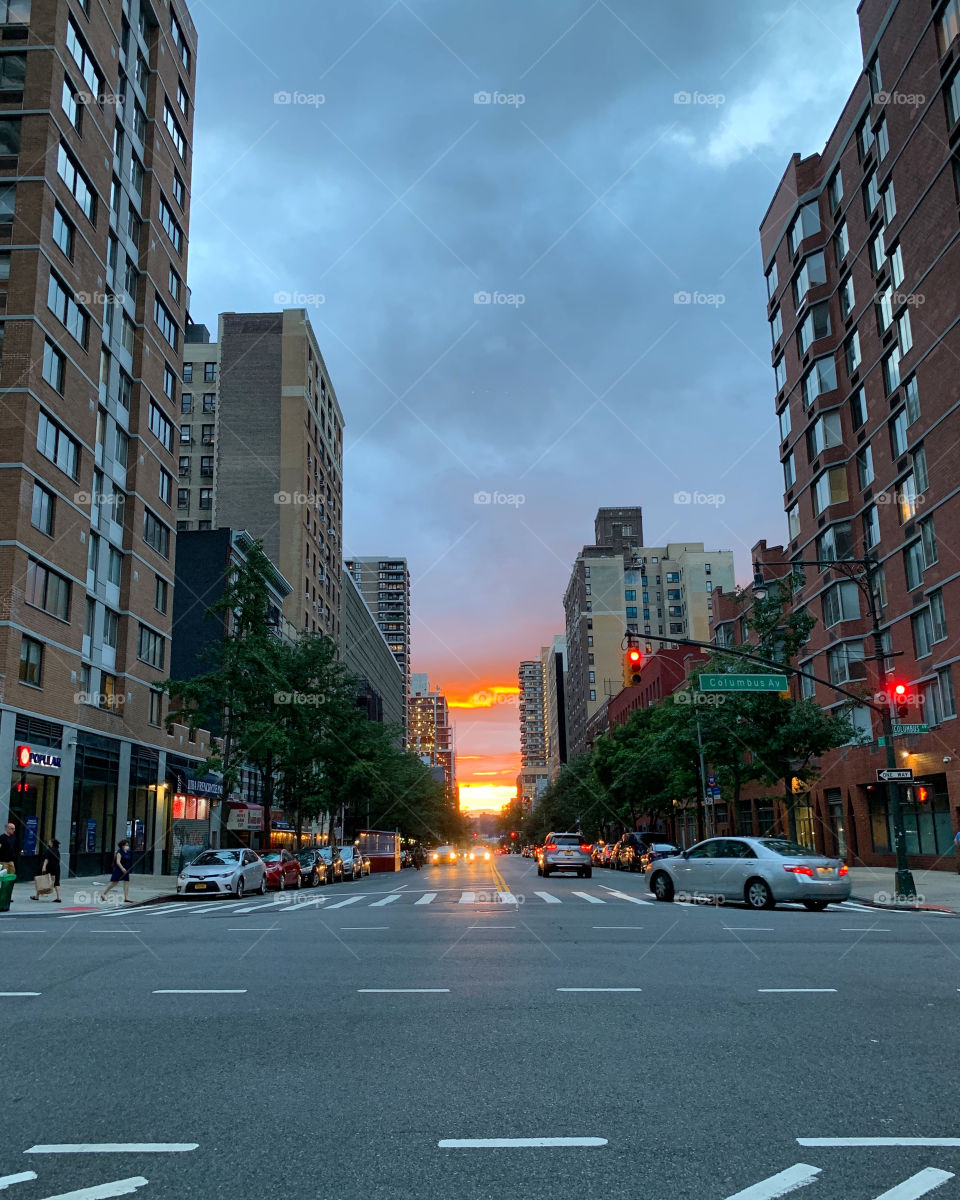 Sundown at the city. The car was turning. People were ready to cross the pedestrian lane. 