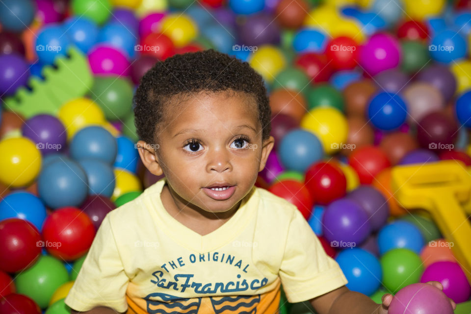 Menino em piscina de bolinha de plástico colorida