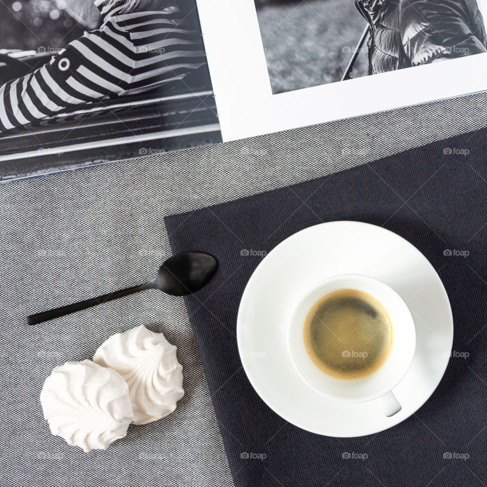 Morning coffee with a fashion magazine. Food photo, square orientation, flat lay. Girl's breakfast: a cup of espresso with a catalog of branded clothes, with marshmallows. Nice breakfast