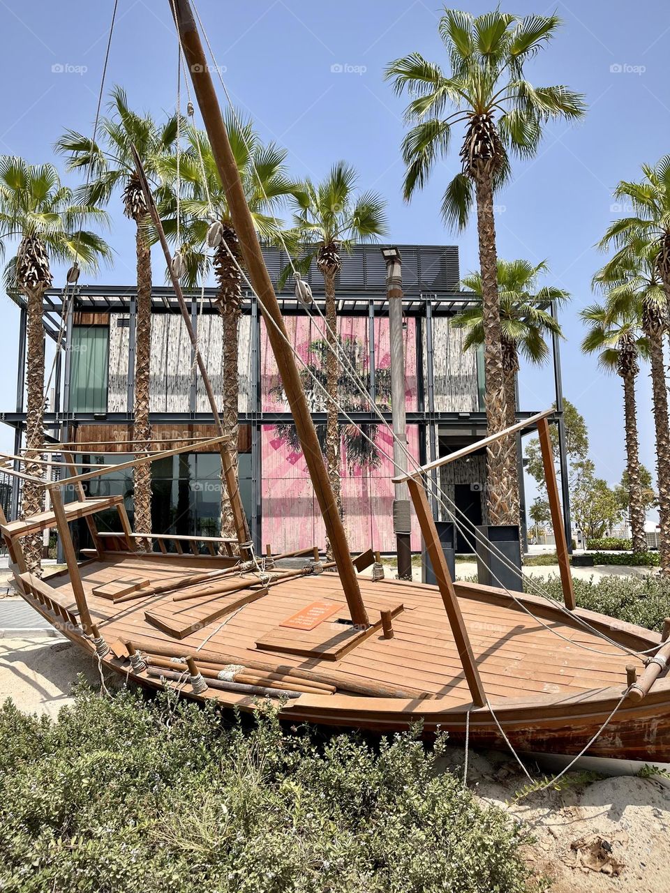 Small wooden boat on the sand in front of a house of modern architecture