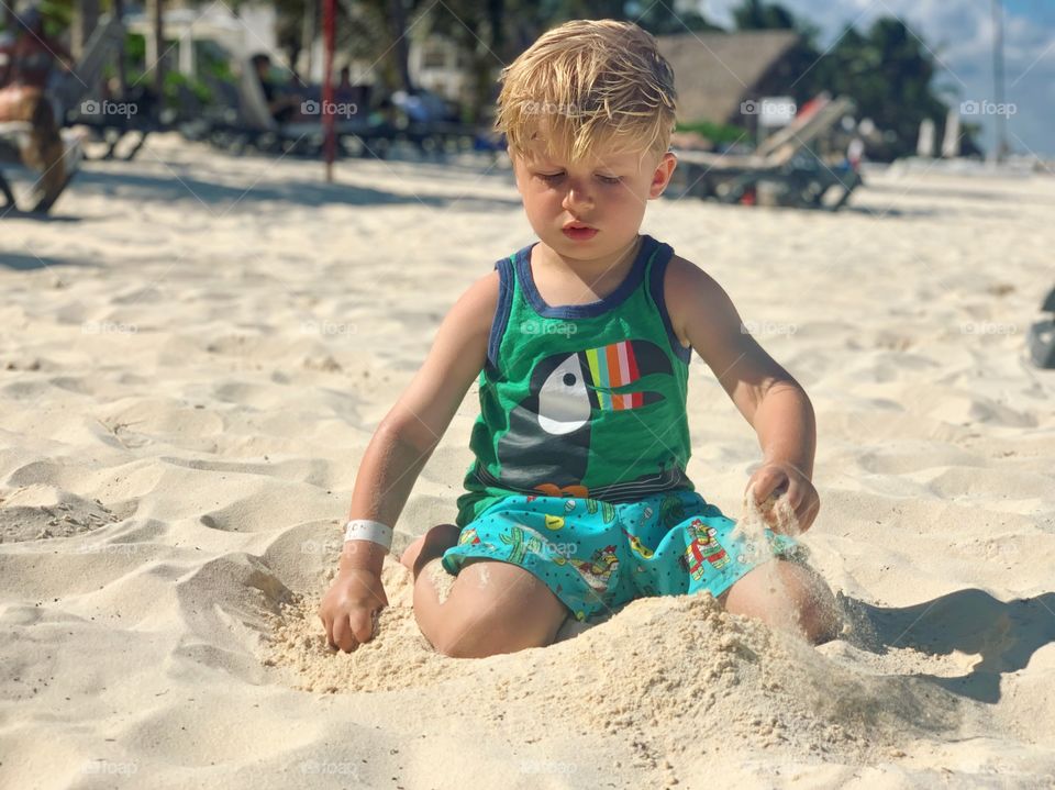 Little boy playing with sand on beach