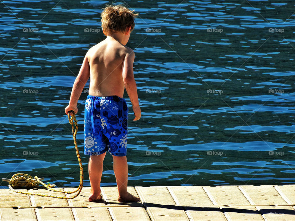 Young boy standing on dock near lake