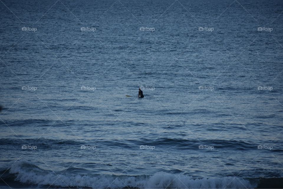 Lone surfer silhouette in Atlantic Ocean