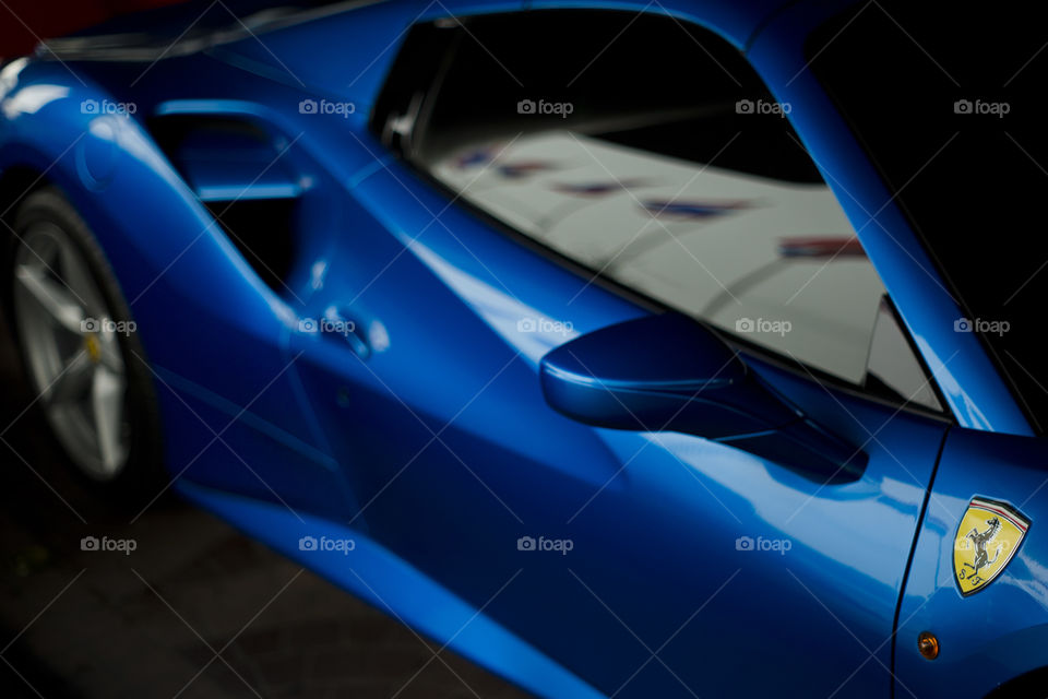 Thai flag reflected on the window of Ferrari 488 spider blue coupe sports car, 3.9 liter V8 twin turbocharged produced by the Italian sports car - Ferrari F154CB V8