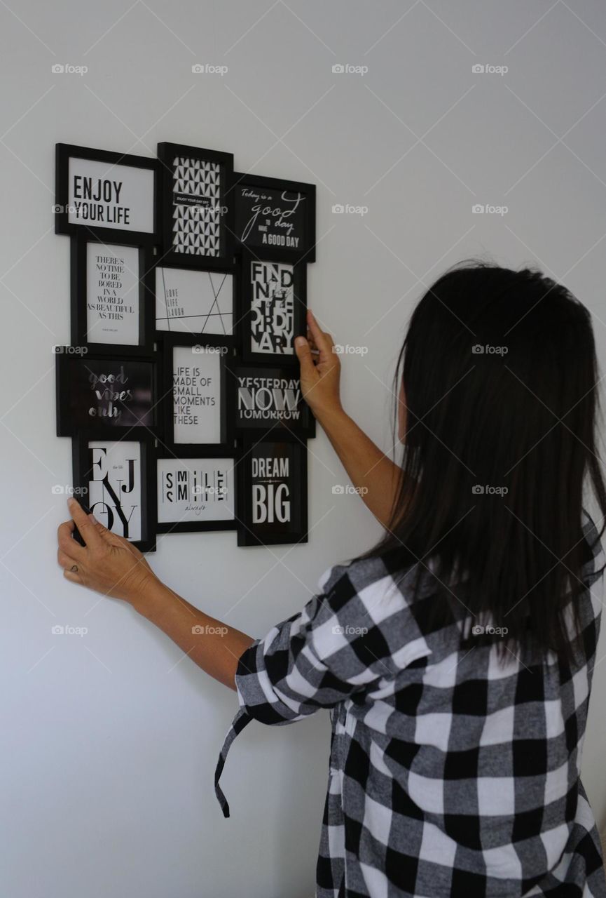 girl at home hangs rectangular photo frames on a white wall