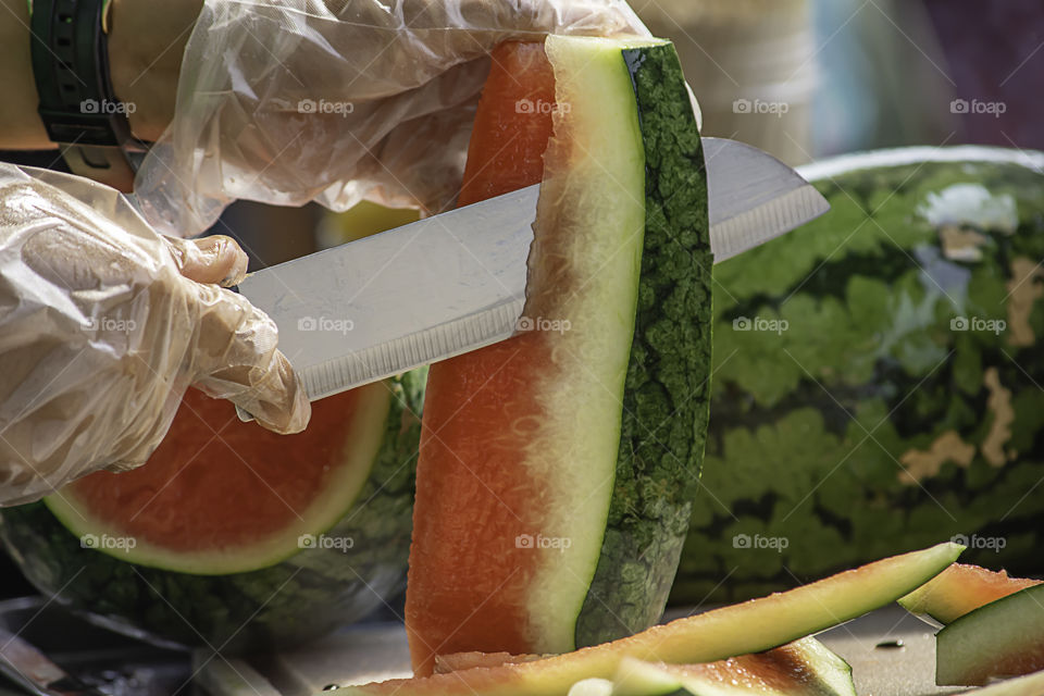 Hand holding red watermelon And use a knife to cut a piece.