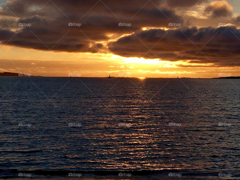 Sun coming out of the ocean illuminating the sky 