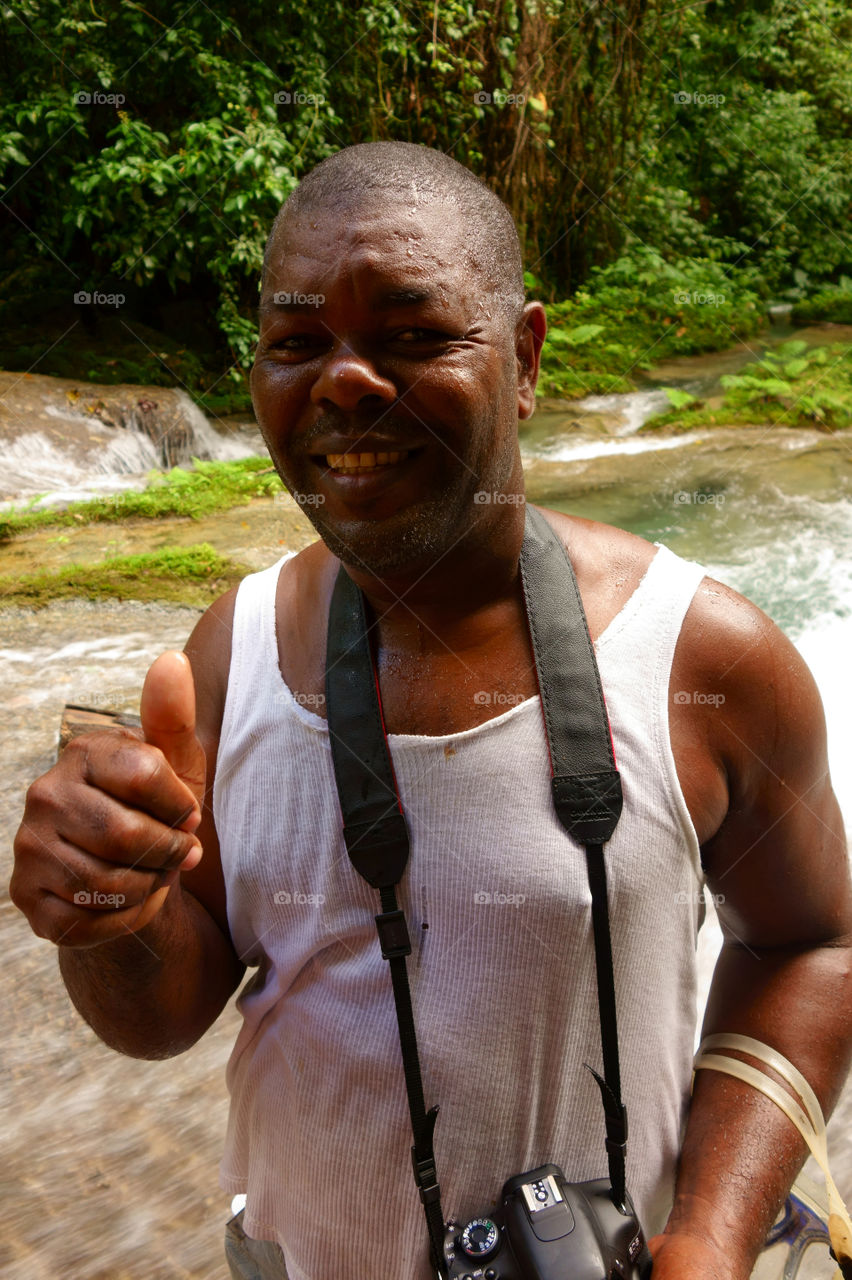 Reach Falls, Jamaica - December 30, 2013 - Unidentified tourist guide at Reach Falls waterfalls with lush tropical rain forests on the background. Reach falls near Port Antonio are one of the most popular tourist destinations and attractions in Portland parish, Jamaica. Photo taken on December 30, 2013