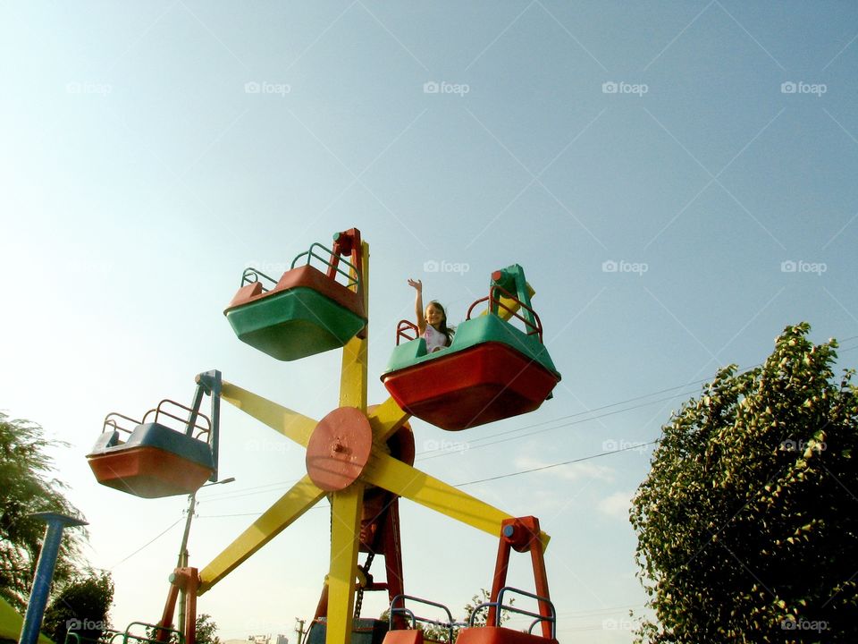 girl rides a carousel and waves her hand