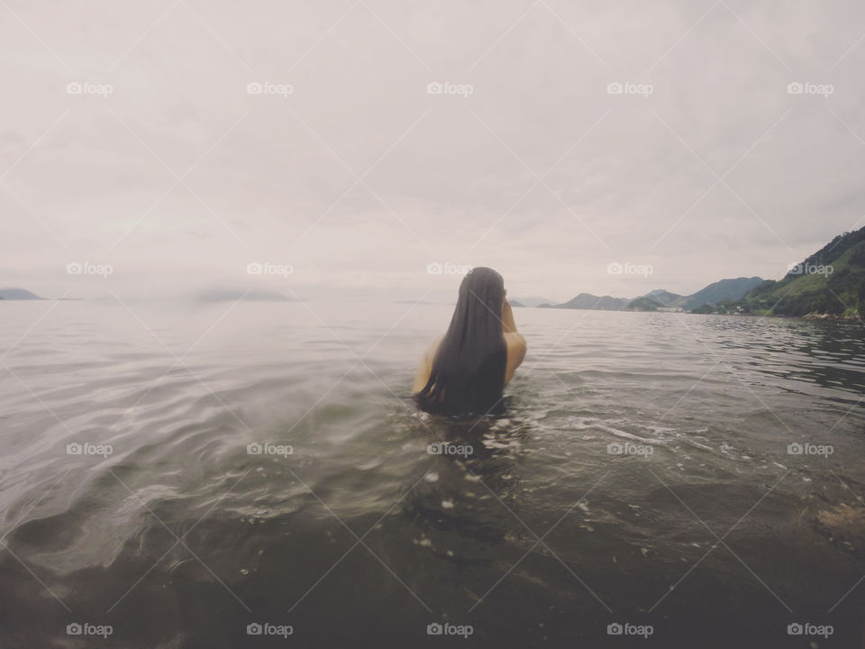Rear view of woman with long hair swimming in sea