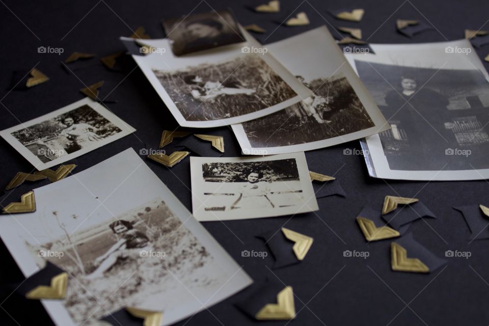 Vintage photo collection in black and white and sepia tones with gold photo mounting corners on a black surface 