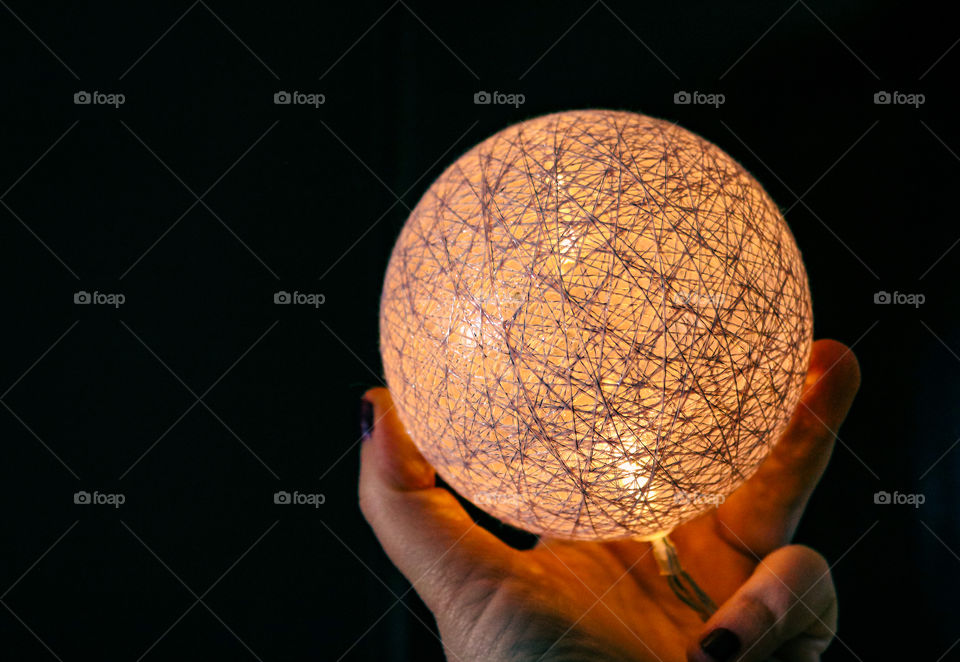 A hand holding a shining ball in the dark