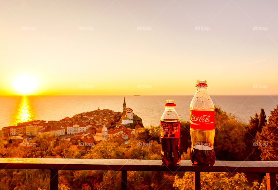 Coca Cola bottles with stunning sunset on background 