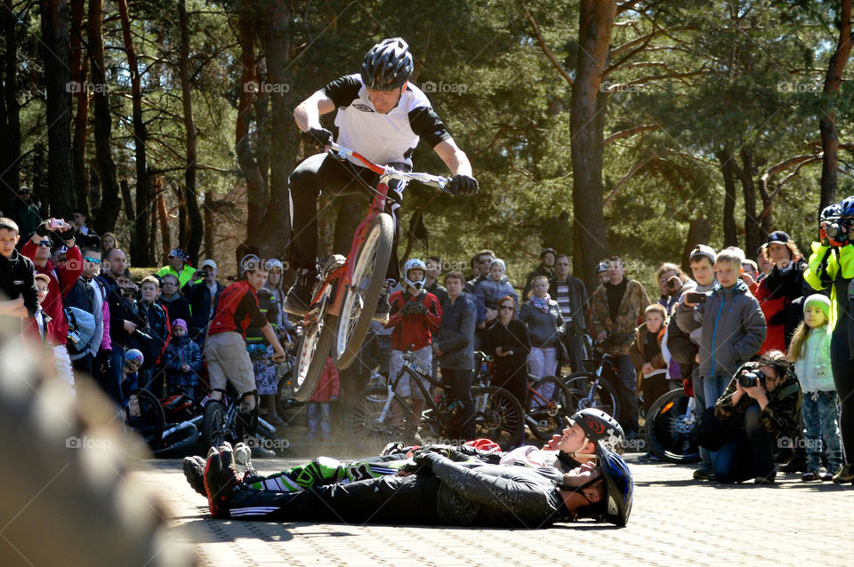MTB trial - jump on the bike through the people lying on the ground