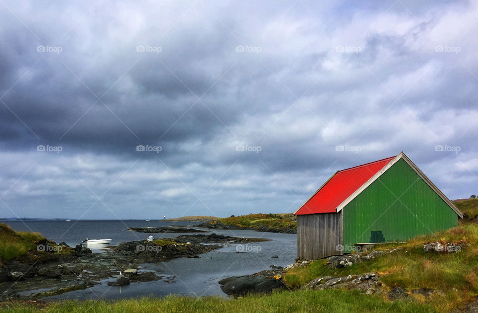 Green house with a red roof on the shore in Haugesund, Norway 