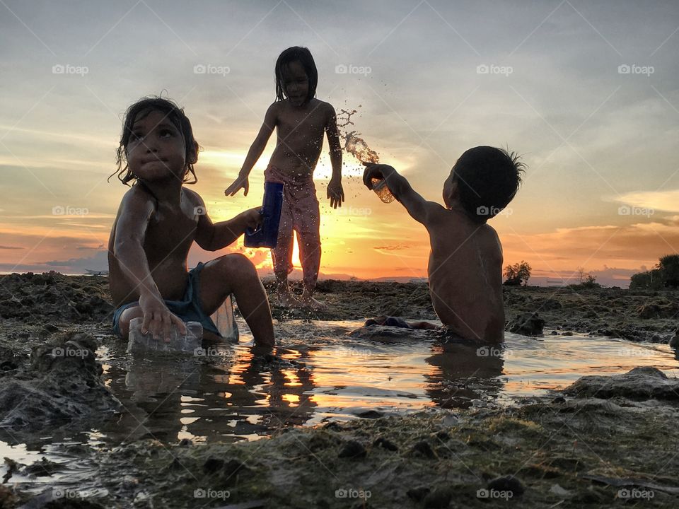 Topless children playing with water at beach