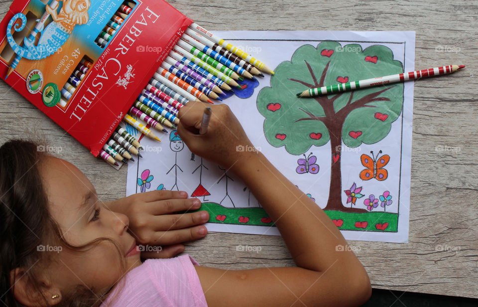 Girl coloring drawing with lapis Faber Castell