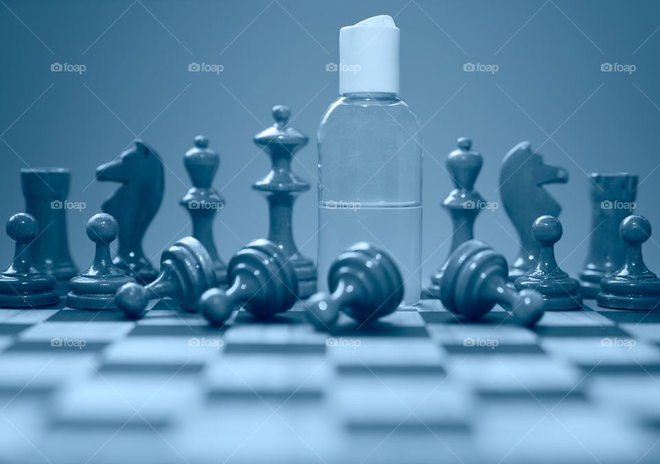 Coronavirus concept image chess pieces and hand sanitizer on chessboard illustrating global struggle against novel covid-19 outbreak.