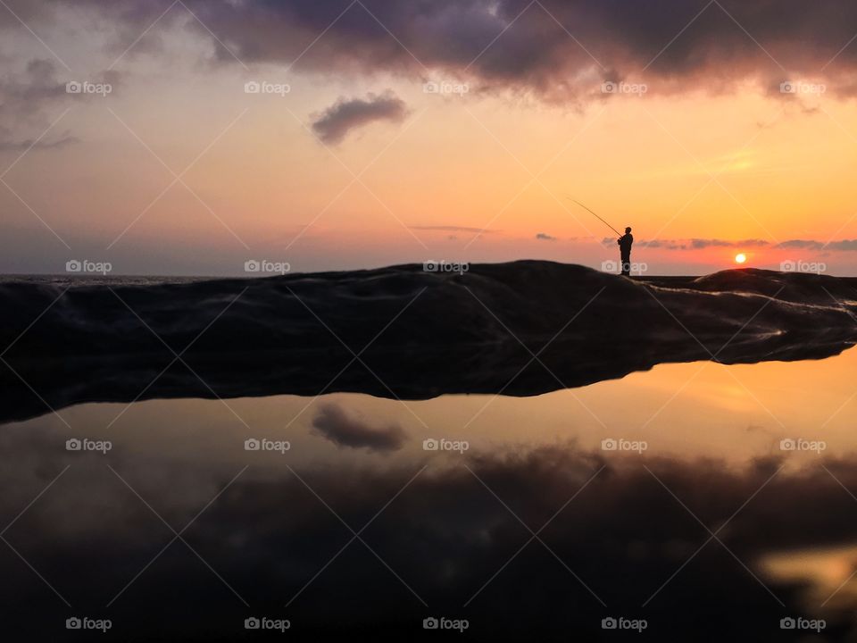 Fisherman fishing at sunset 