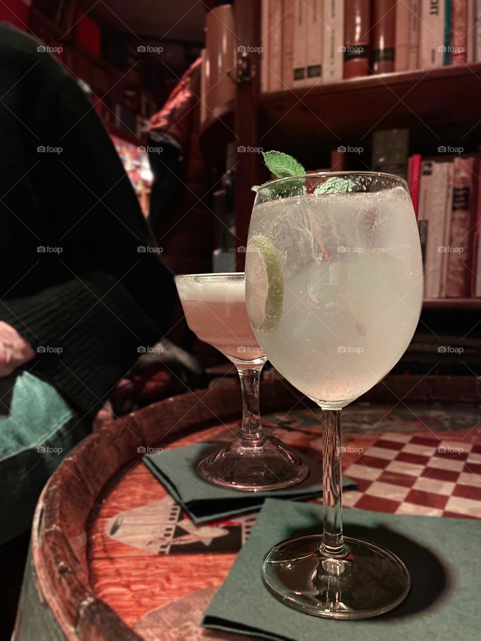 Elegant drinks served in a cozy library-themed bar. A perfect mix of sophistication and comfort, captured in warm lighting with bookshelves as the backdrop. Ideal for those who love unique bar concepts and intimate atmospheres.