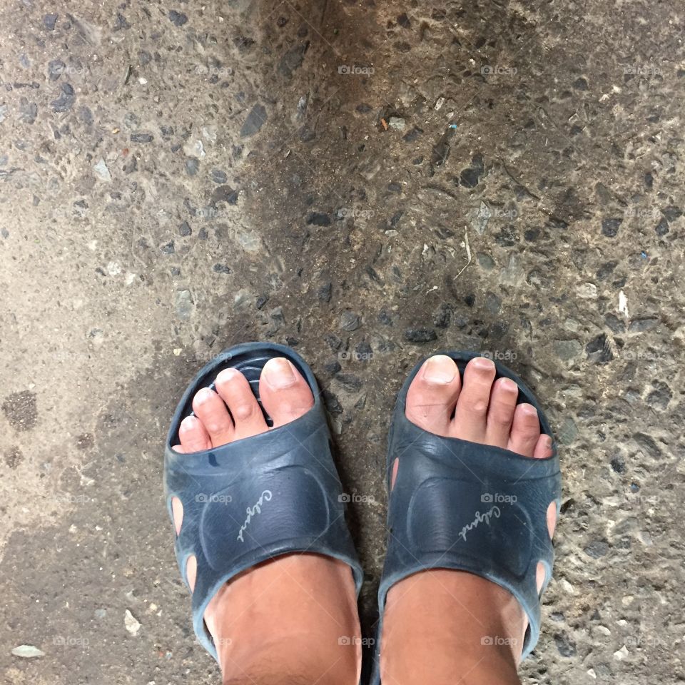 Man feet wearing blue flip flops great for any use.