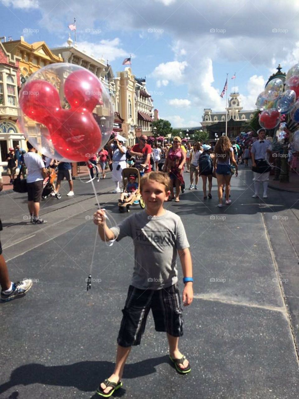 Boy standing on street holding balloon