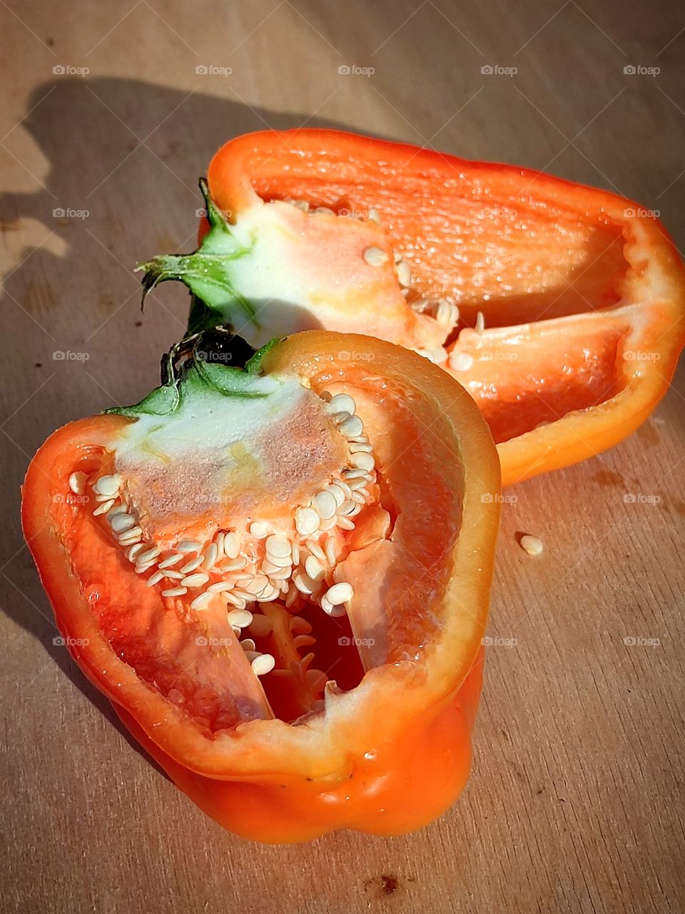 Sunbeams on an orange bell pepper that has been cut in half.  Juicy pepper