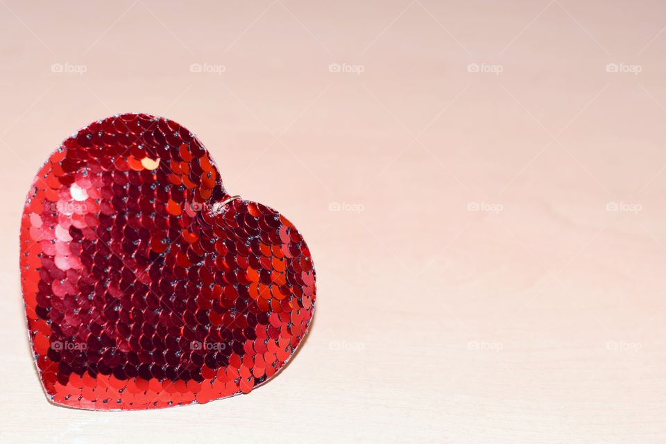 Red heart from sequins on a light background.