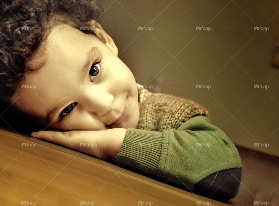 Close-up of a boy resting his head on table