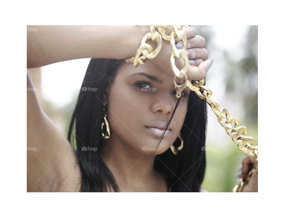 latin girl with golden chain. beauty portrait of latina th big golden chain in her hands