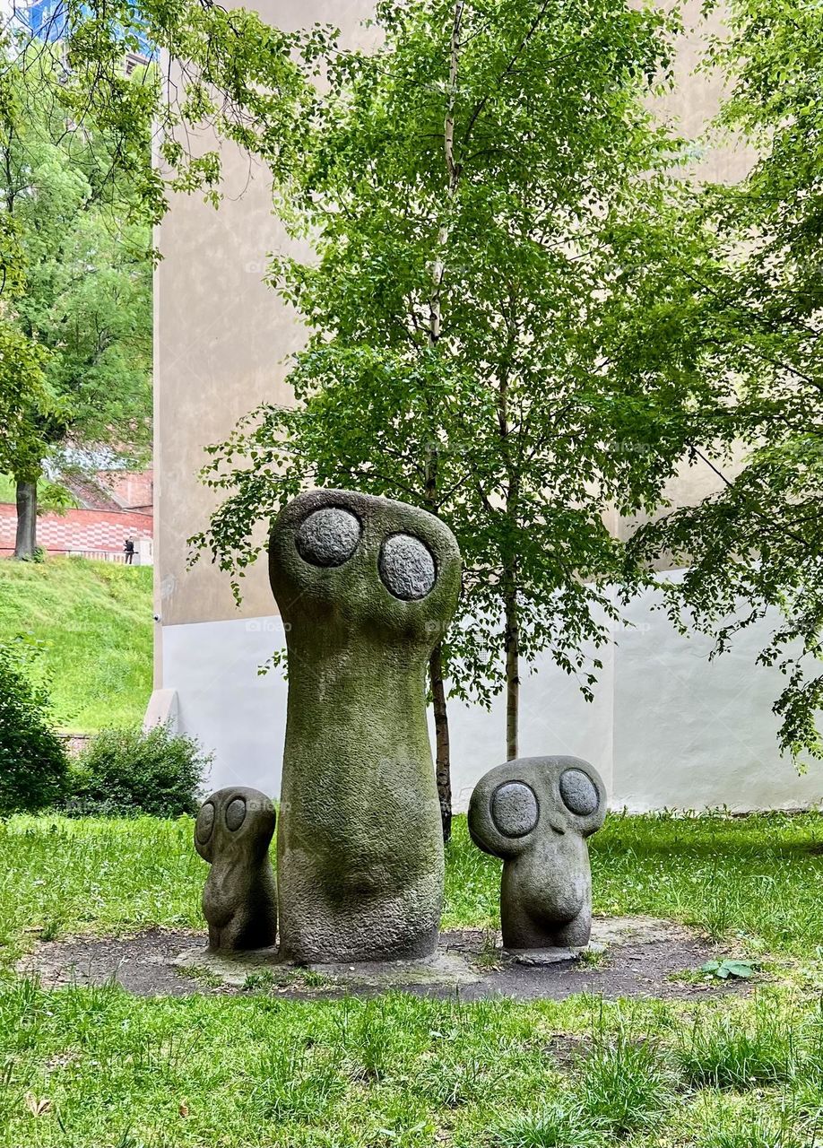 Sculpture "Owl" in Krakow. One is tall, and on either side of it are two smaller ones. they are carved from sandstone with granite eyes.