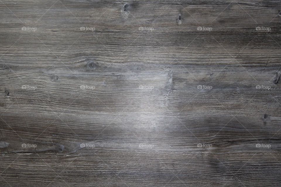 A gray wooden surface that is used as a background with a light feeding from the left side.