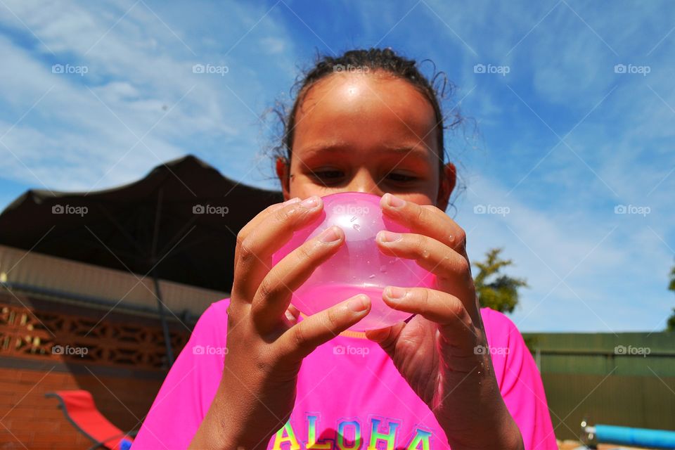 Girl with pink water balloon. Girl with pink water balloon, backyard pool fun