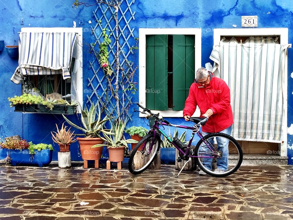 The man and his bike. The colorful life of Burano was enhanced by the vibrant red of this man's coat against his cool blue house. 