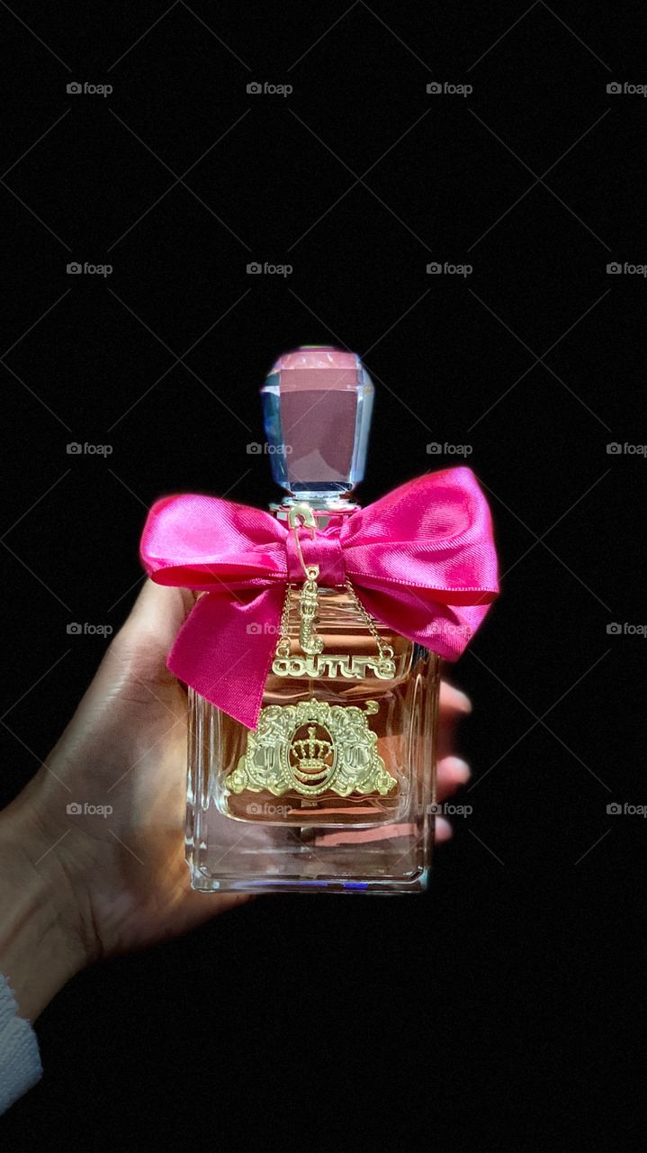 A woman holding a Viva La Juicy Perfume with black background.