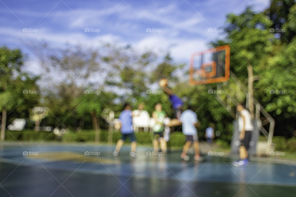 Blurry image of elderly men and teens playing basketball in the morning at BangYai Park , Nonthaburi in Thailand.