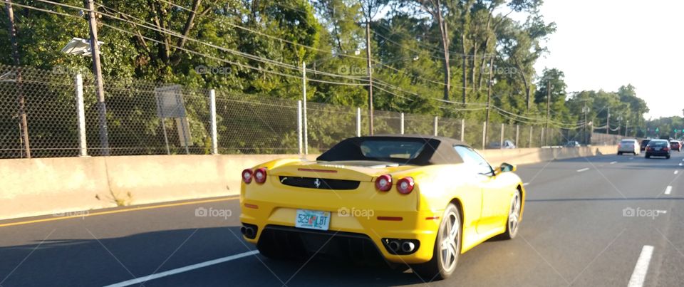 Yellow Ferrari races down the highway.