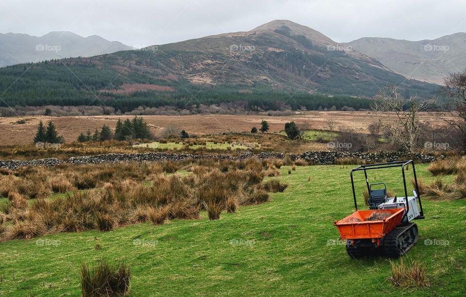 Beautiful landscape scenery with machinery on green meadow and mountains in the background at Connemara National park in county Galway, Ireland