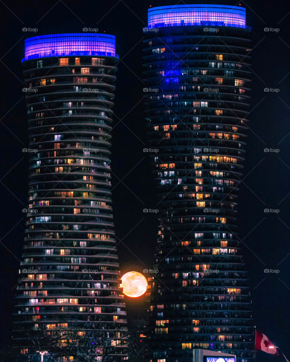 Full moon rising inbetween two unique shaped towers, with a clear dark night sky in the background