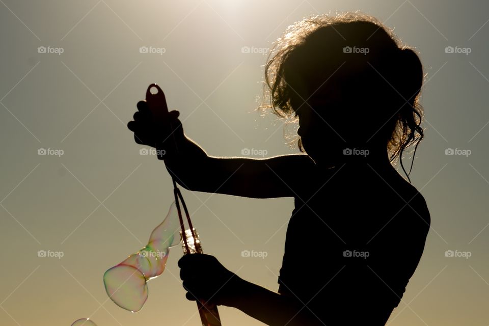 A silhouette of a girl making bubbles with soap on the beach 