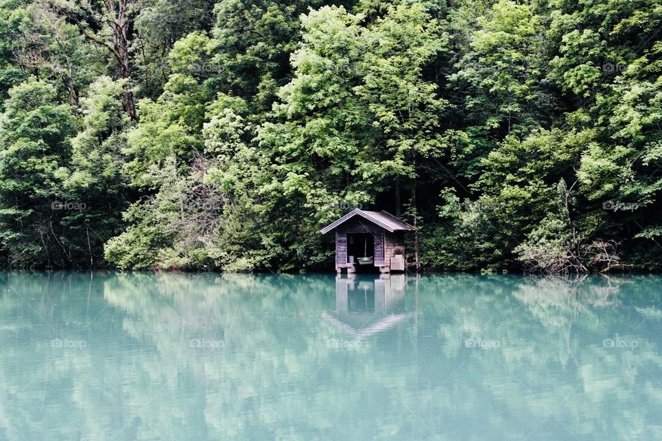 A boat shed on the shore of a turquoise mountain lake 