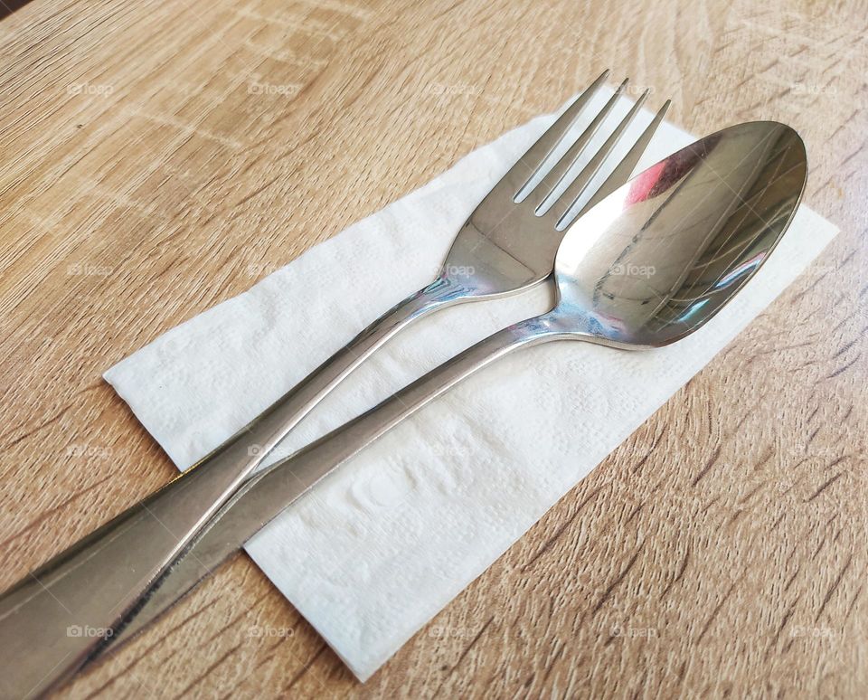 Cutlery. Spoons and forks in tissue on a wooden table background