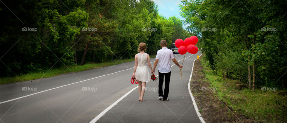Just married are walking with red balloons