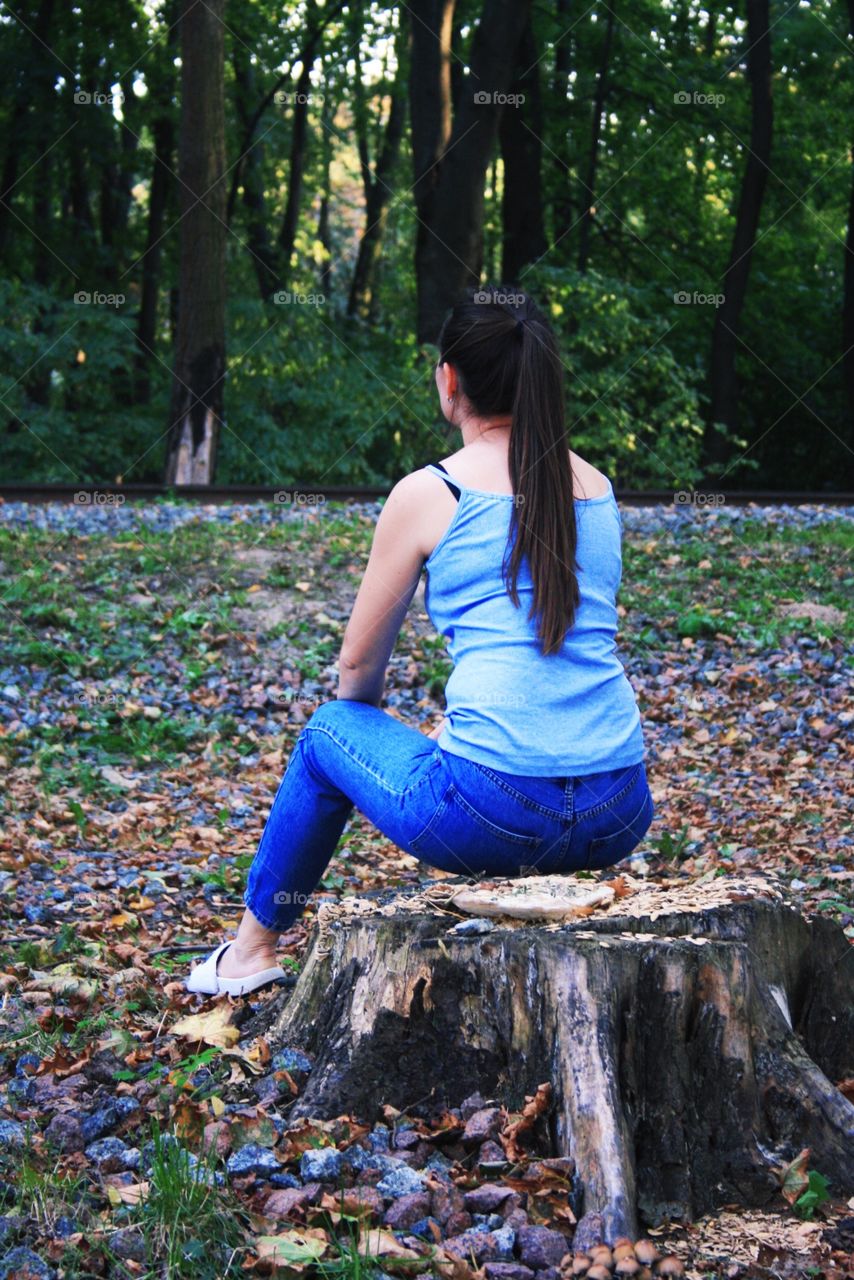 The girl is sitting on a stump