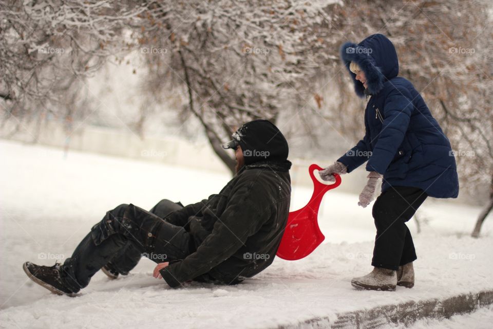 Dad and daughter ride a hill in winter